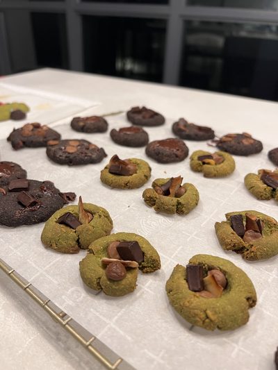 Matcha green and dark chocolate thumbprint cookies pressed with chunks of chocolate, cooling on parchment paper